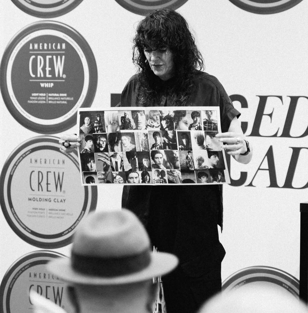 Phoenix Thomson holding a collage of people in front of an American Crew advertisement.