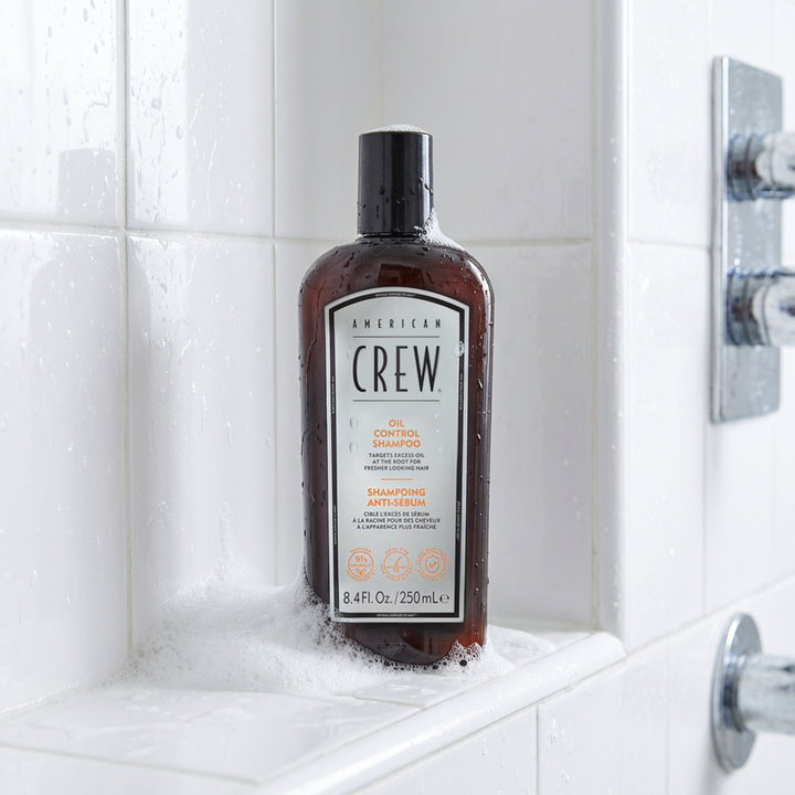 Bottle of American Crew Oil Control Shampoo on a tiled bathroom shelf
