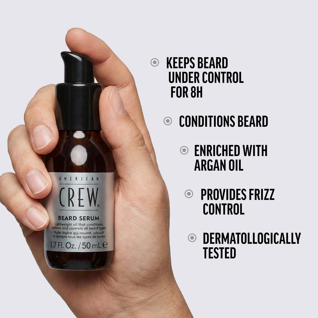 Hand holding a bottle of American Crew Beard Serum with product features listed on a light gray background.