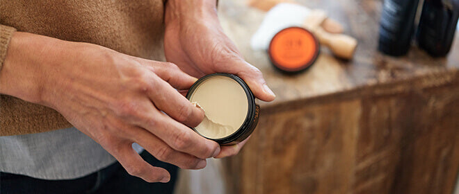 Man uses American Crew Matte Clay with other American Crew products on table in background.