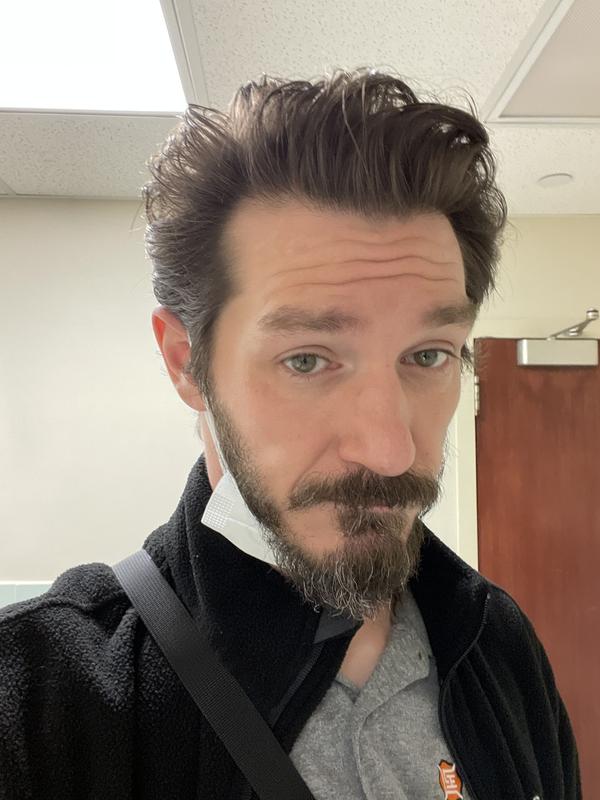 Image of American Crew Matte Clay Reviewer Green, with styled hair, a grey polo shirt, and a black sweater.